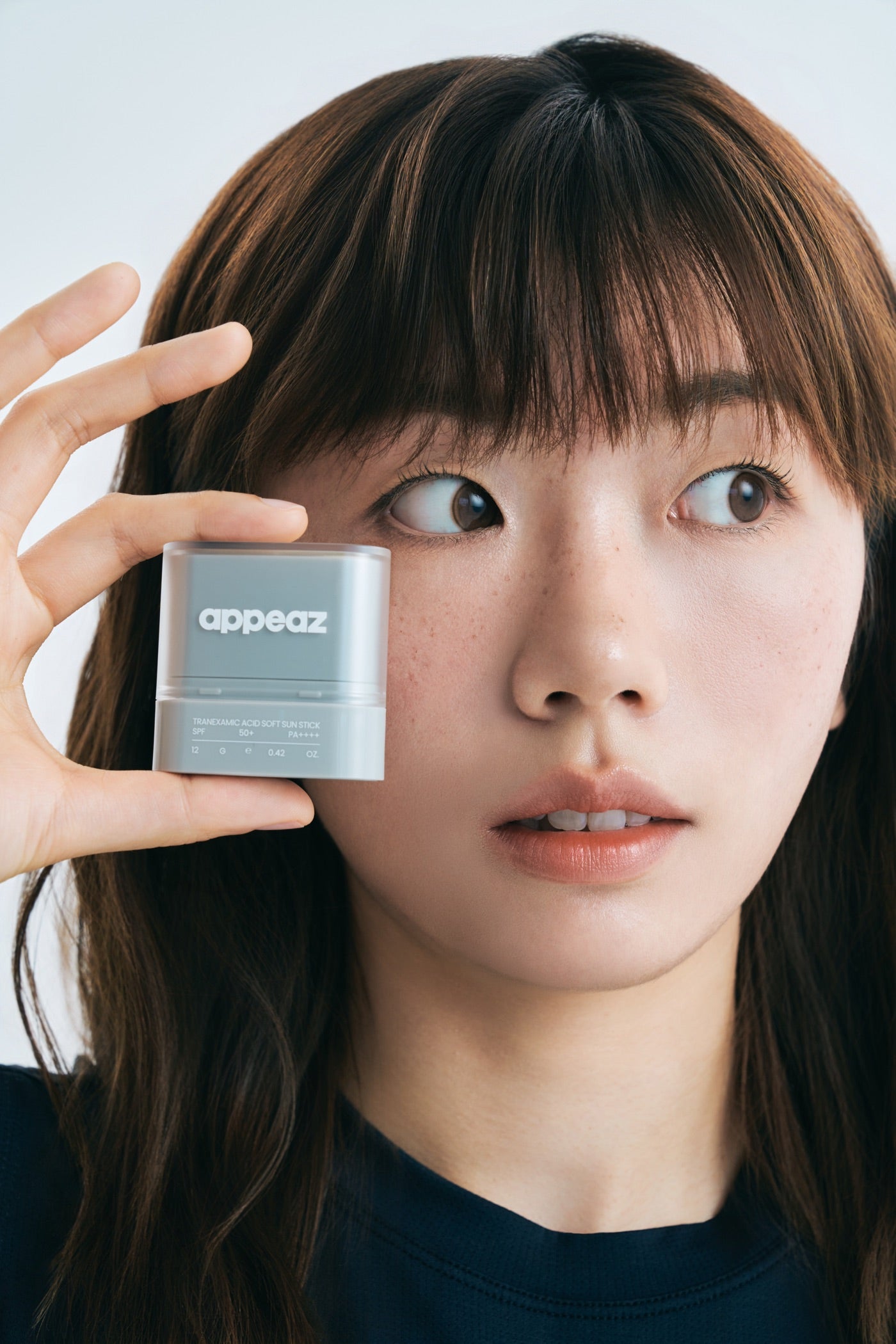model holding the appeaz sun stick beside her face
